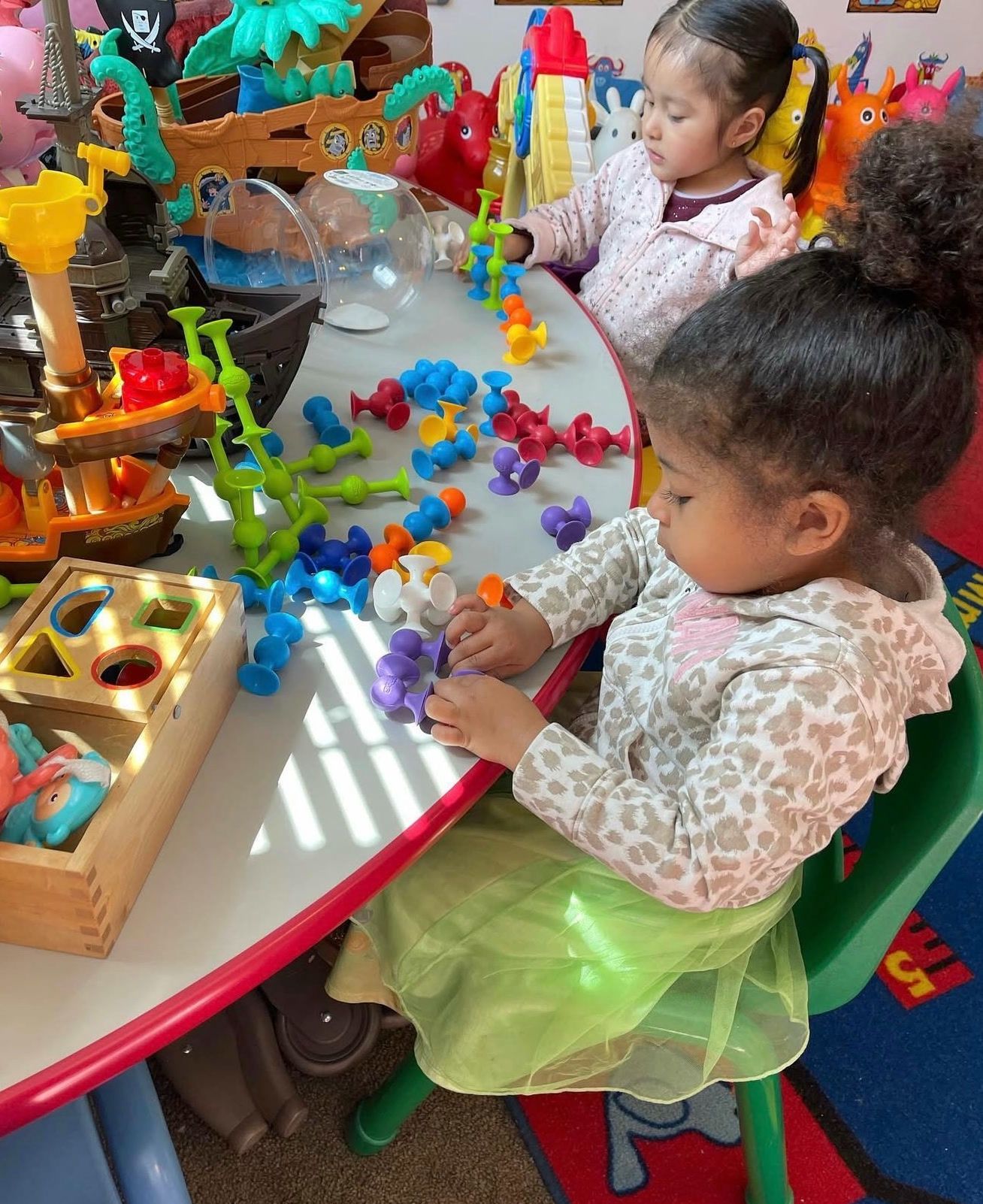 Two girls building shapes with colorful suction toys