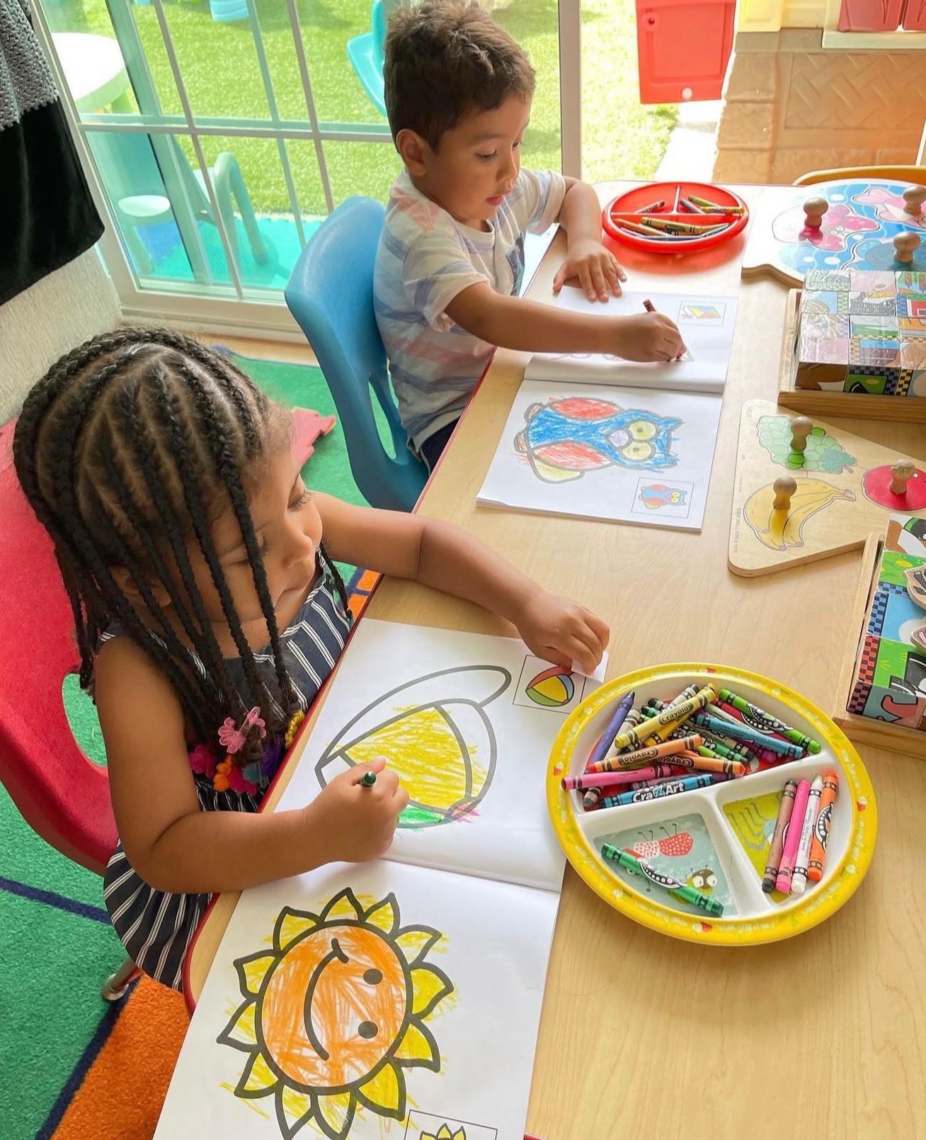 Two children coloring a sun and a bird with crayons