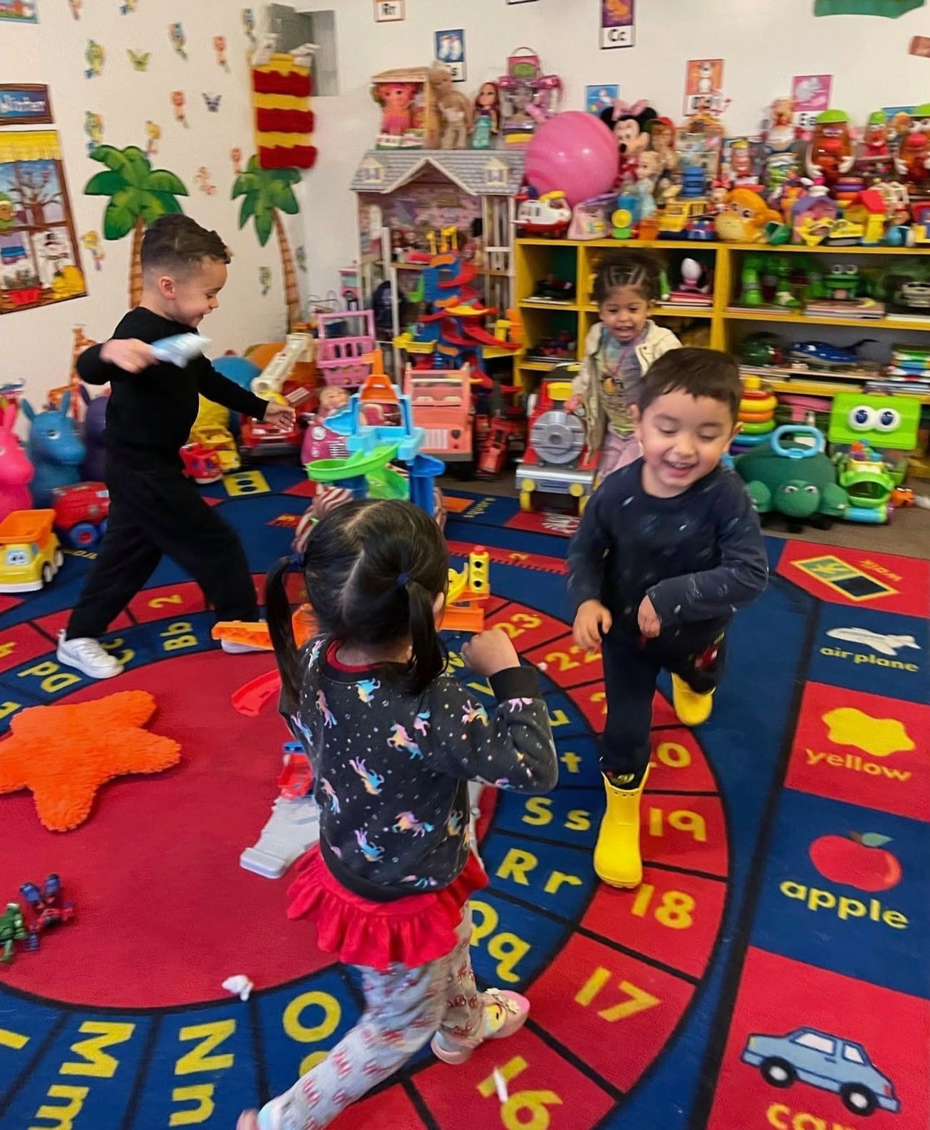 Kids dancing and laughing together on a colorful alphabet rug in the playroom