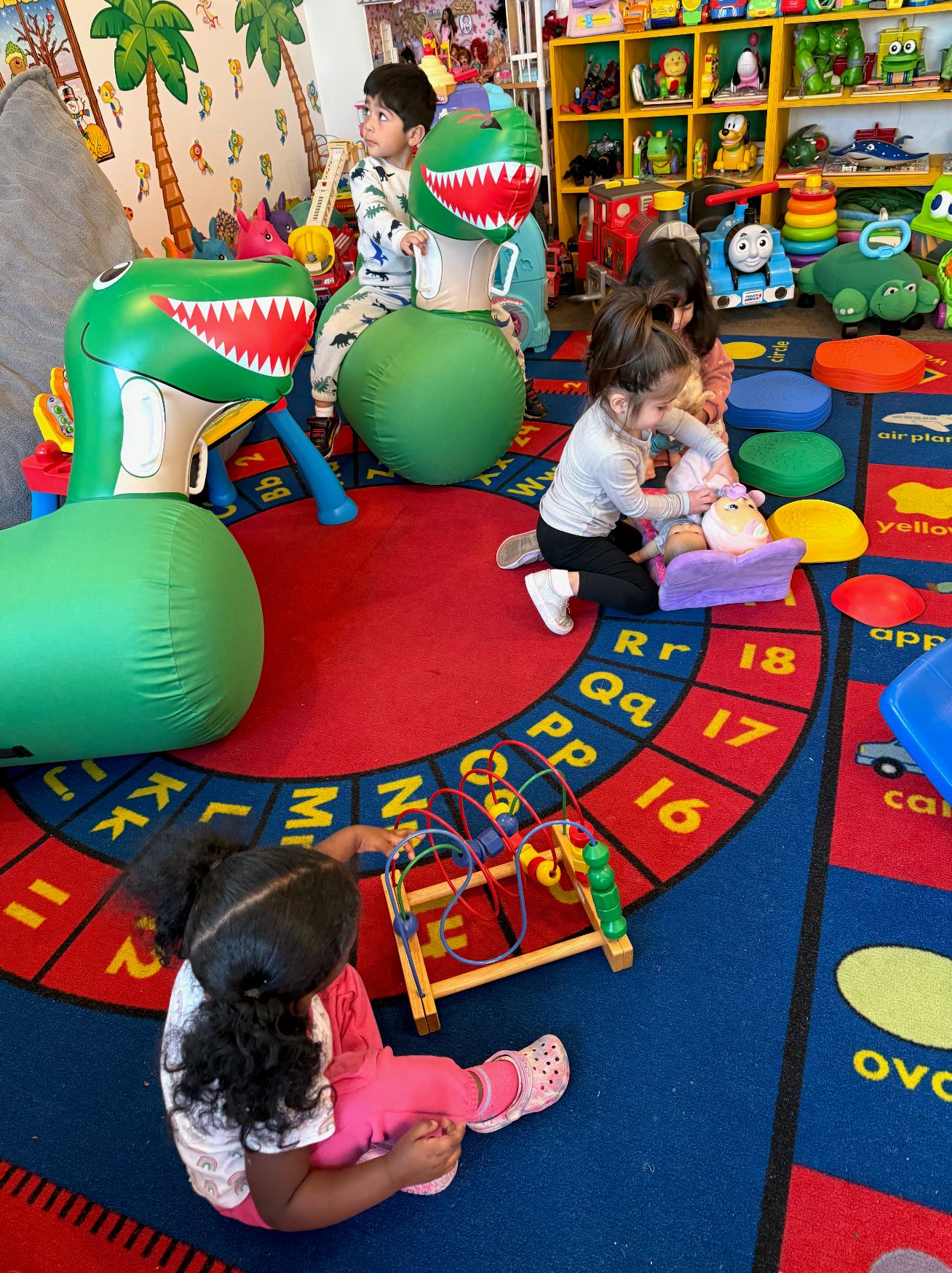 Kids playing with inflatable dinosaurs on a letter and number rug