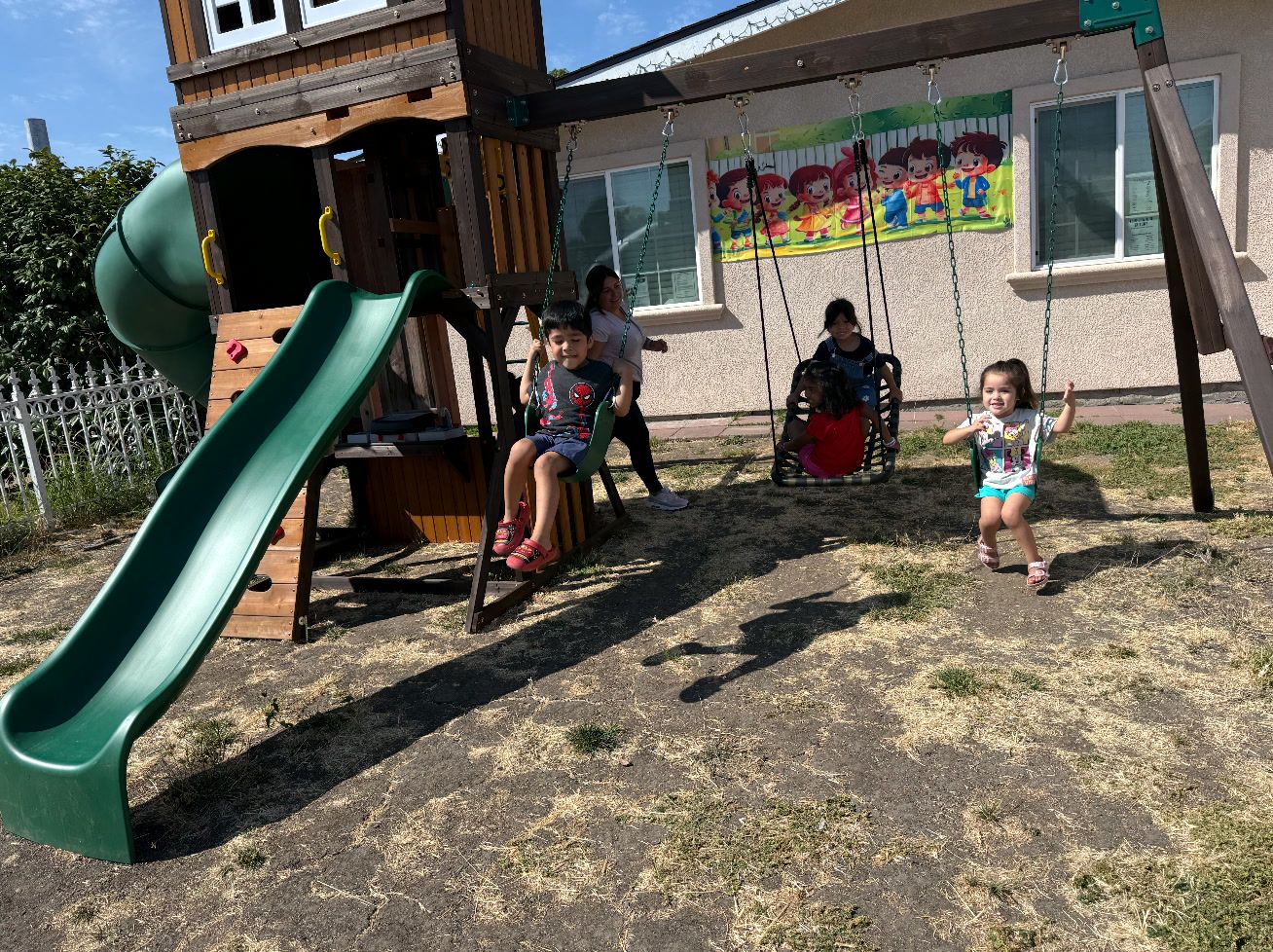 Kids on the swings next to the wooden play structure